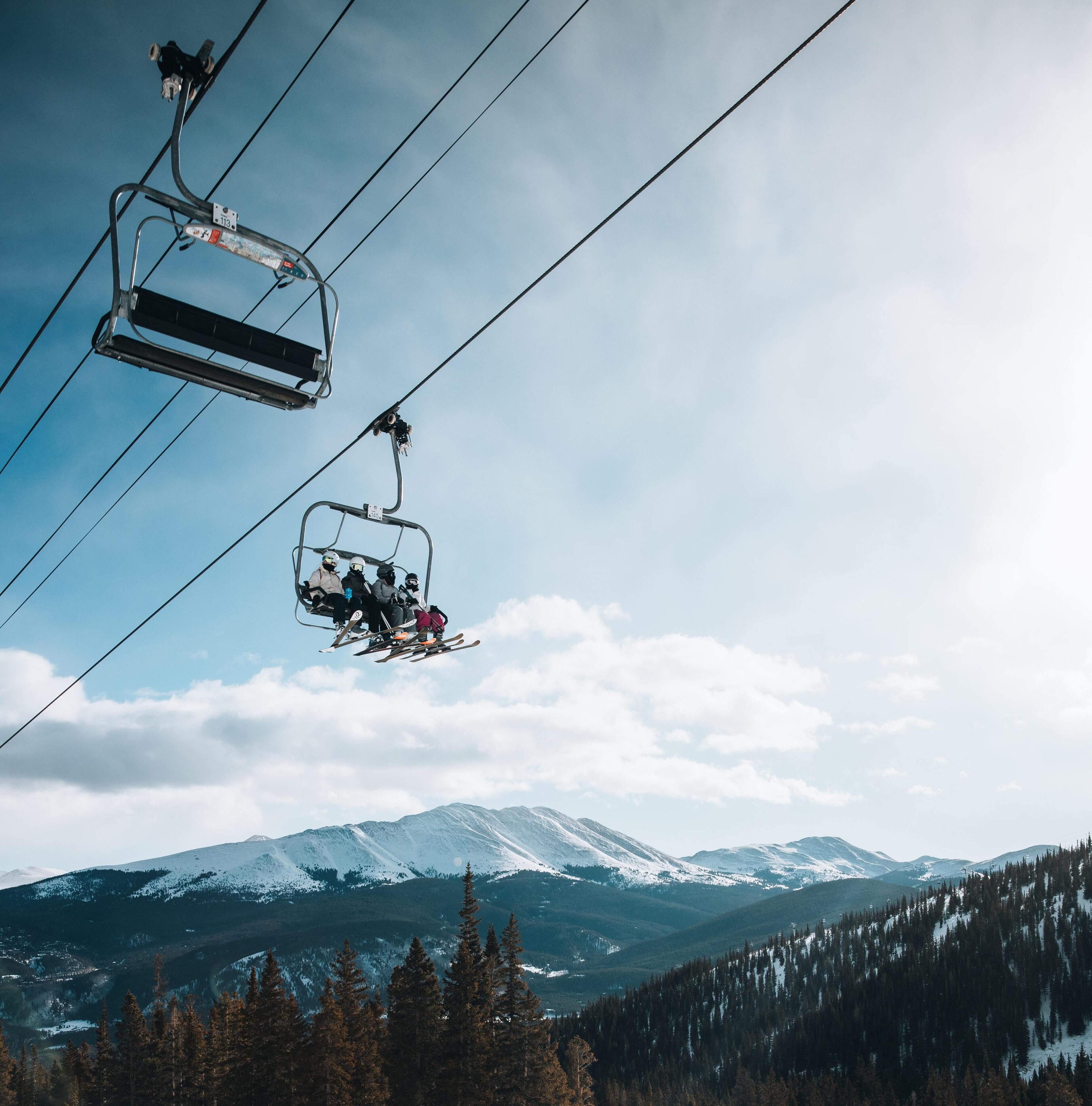 A ski lift with skiers in a mountainous landscape.