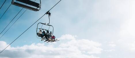 A ski lift with skiers in a mountainous landscape.