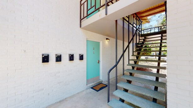 A staircase with a metal railing leading to a door marked with the number 2. - Atlantic Breeze #2 2 bedrooms, 1 bath (Jekyll Island)