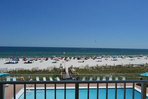 Strandudsigt med pool og liggestole.