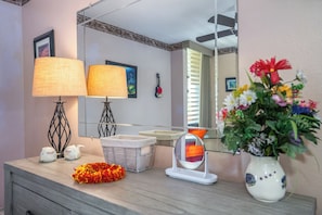 Een badkamermeubel met een spiegel, twee lampen, een vaas met bloemen, een gitaar en een decoratief wandobject.