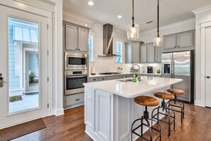 A modern kitchen with a central island, stainless steel appliances, and pendant lighting.