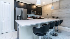 Una cucina moderna con mobili scuri, elettrodomestici in acciaio inossidabile e un'isola centrale con sgabelli da bar.