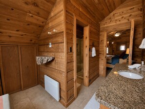 A wooden cabin interior with a bathroom featuring a granite countertop sink, a towel rack, and a shower area. - Cozy Condo Across from Main Village & Slopes, Pool/Spa/Workout Included (Durango)