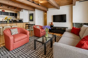 A modern living room with a sofa, armchairs, a coffee table, and a TV.