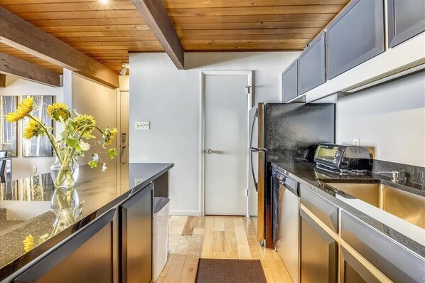 Enjoy cooking in this kitchen with a stainless steel refrigerator, black countertop, and oven.