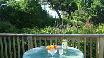 A round table with a green tablecloth, a bottle, and a glass on it.