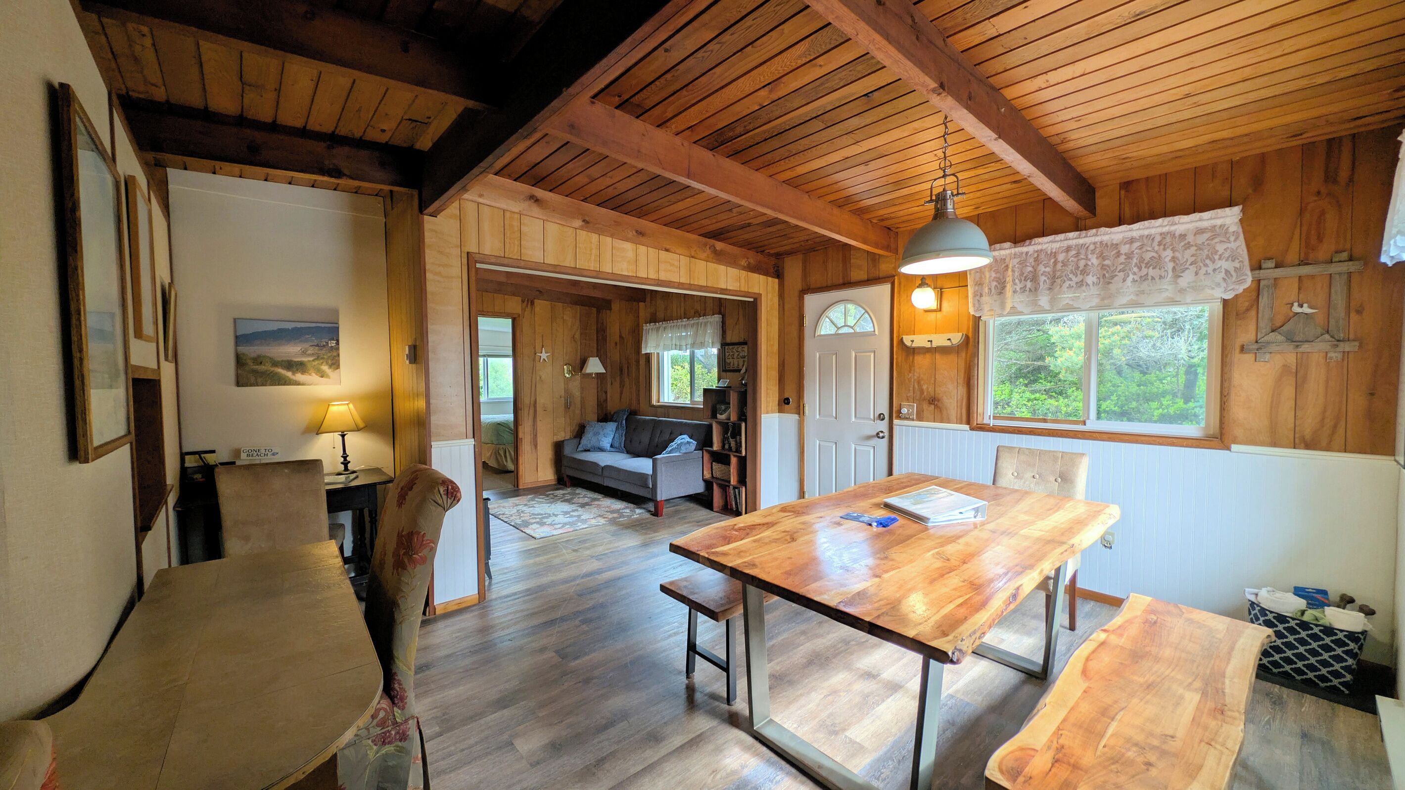 L’intérieur d’un chalet chaleureux, avec une table à manger en bois, un canapé et une lampe.