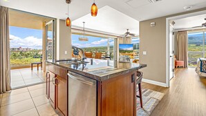 Una cocina moderna con una isla grande, un comedor con vistas y una sala de estar amplia con ventilador de techo.