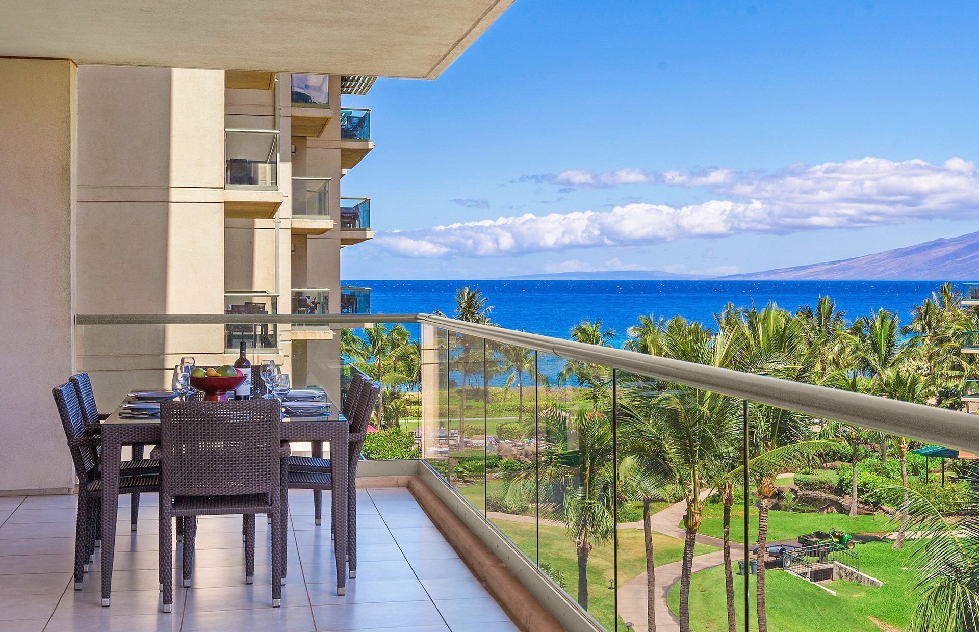 Ein Balkon mit Esstisch, Stühlen und Blick auf das Meer und Grünflächen.