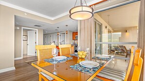 Comedor con una mesa de vidrio, sillas de mimbre y vistas a un balcón con sillones.