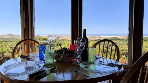 Une table à manger, dressée pour deux personnes avec des assiettes, des couverts et des verres, et offrant une vue sur un paysage magnifique.
