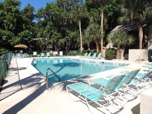 Une piscine avec des chaises longues et un panneau indiquant qu’il n’y a pas de sauveteur de service.