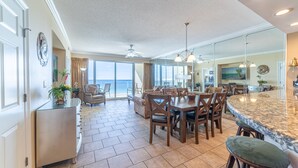 A spacious kitchen with a large island, dining area with chairs, and a view to the outside.