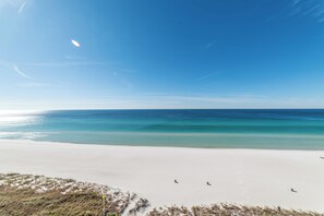 A beach with white sand and clear blue water.