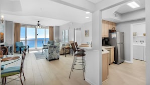 A modern apartment with a dining area, kitchen, and a balcony with a view of the sea.