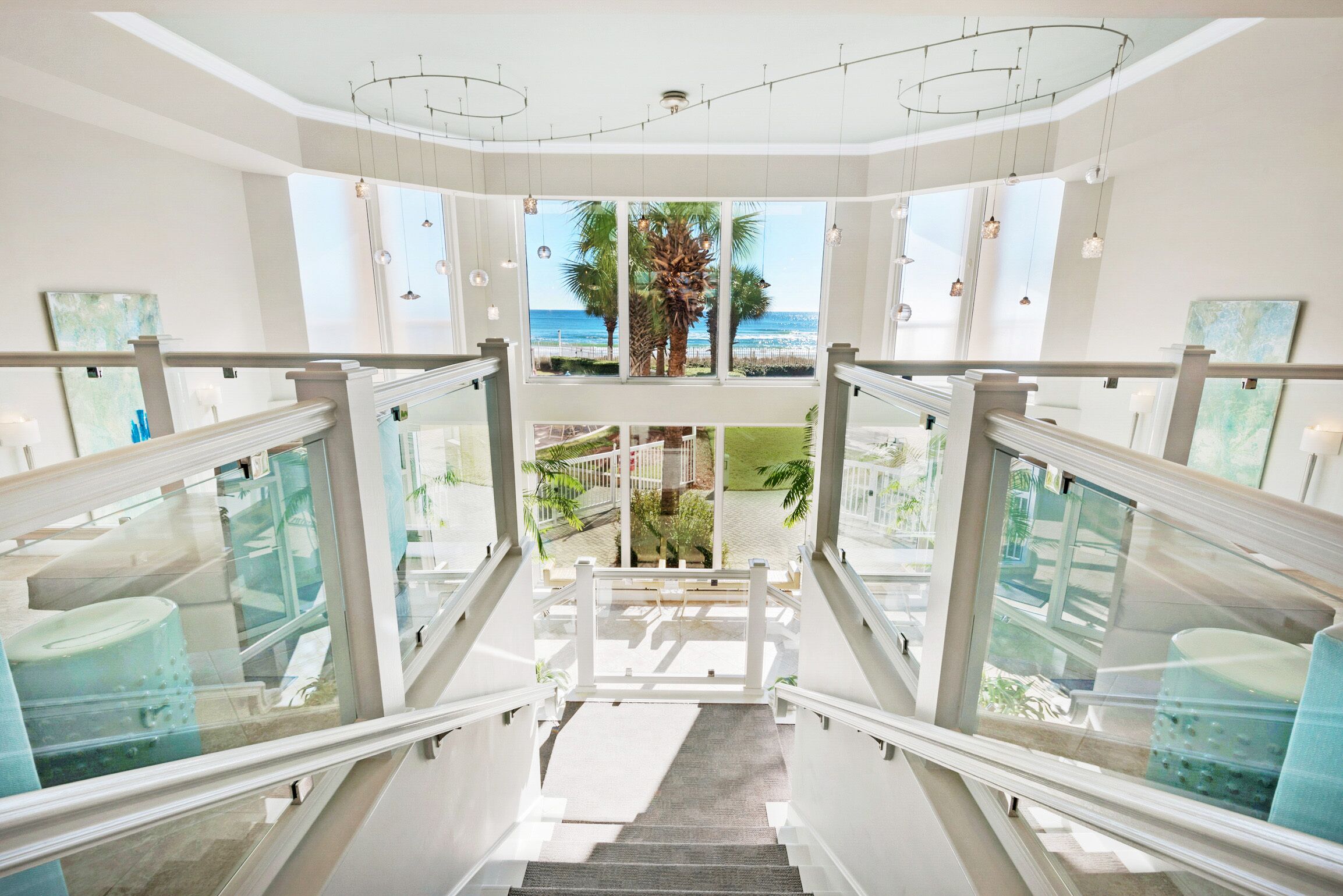 Eine Treppe führt zu einem Balkon mit Blick auf das Meer und Palmen.