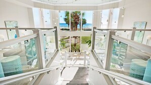A staircase leading to a balcony with a view of the ocean and palm trees.
