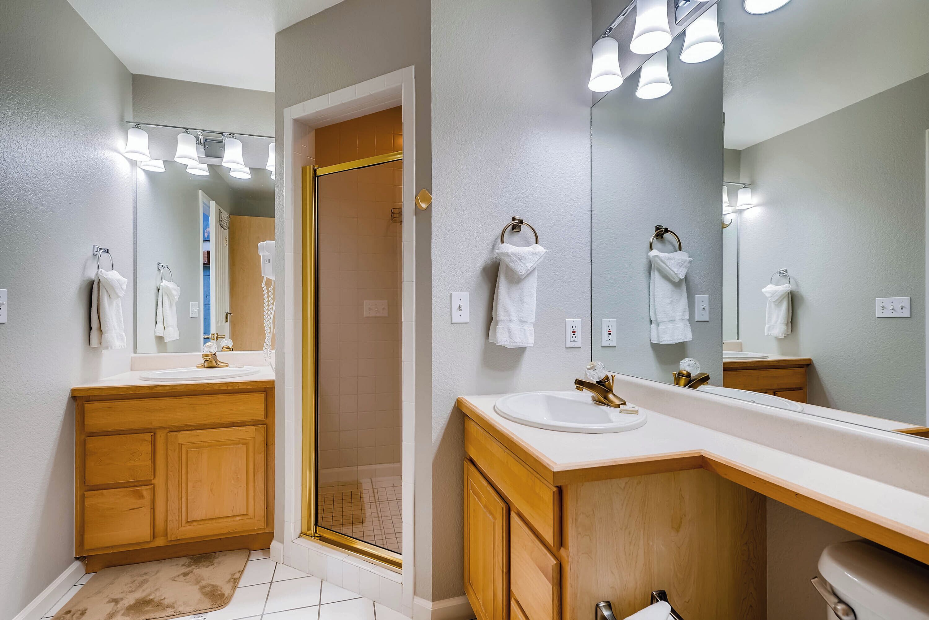 A modern bathroom with a wooden vanity, a large mirror, and a walk-in shower.