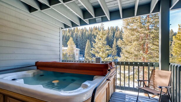 A hot tub on a wooden deck with a view of a forest.