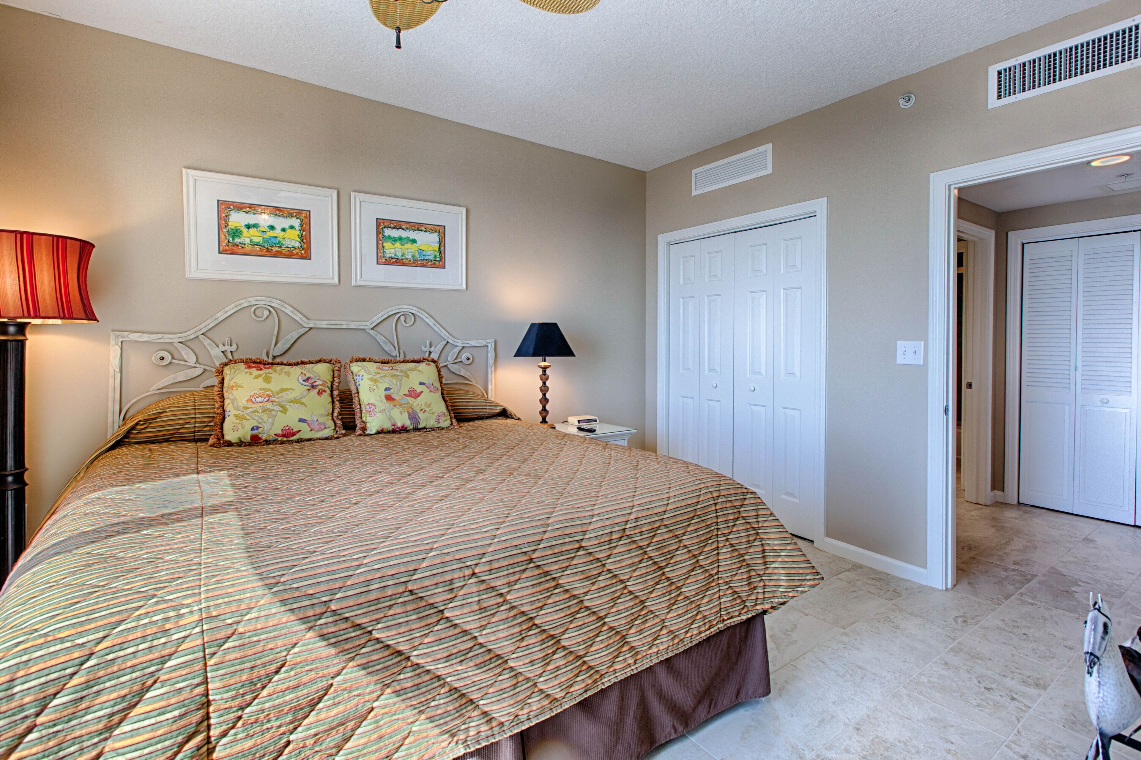 A bedroom with a large bed, two wall-mounted lamps, and two framed pictures.