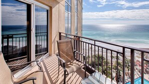 Un balcón con vista al océano, una piscina y sombrillas de playa.