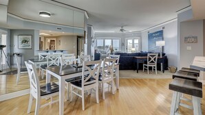 A spacious living area with a dining table and chairs, a sofa, and a kitchen in the background. - 4506 Windsor Court - 5th Floor - Serenity at its best.  AMAZING VIEWS! (Hilton Head Island)