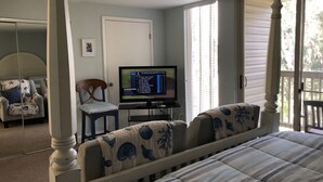 Une chambre à coucher avec un lit, une télévision, une chaise et une fenêtre avec des stores.