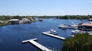 A marina with several boats docked at piers, surrounded by greenery and buildings. - Waterfront, RIVERS EDGE CONDO #1B-BLDG 2 PRIVATE DOCK and ASSIGNED BOAT SLIP! (Steinhatchee)