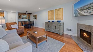 Una sala moderna con chimenea, un comedor y una cocina al fondo.