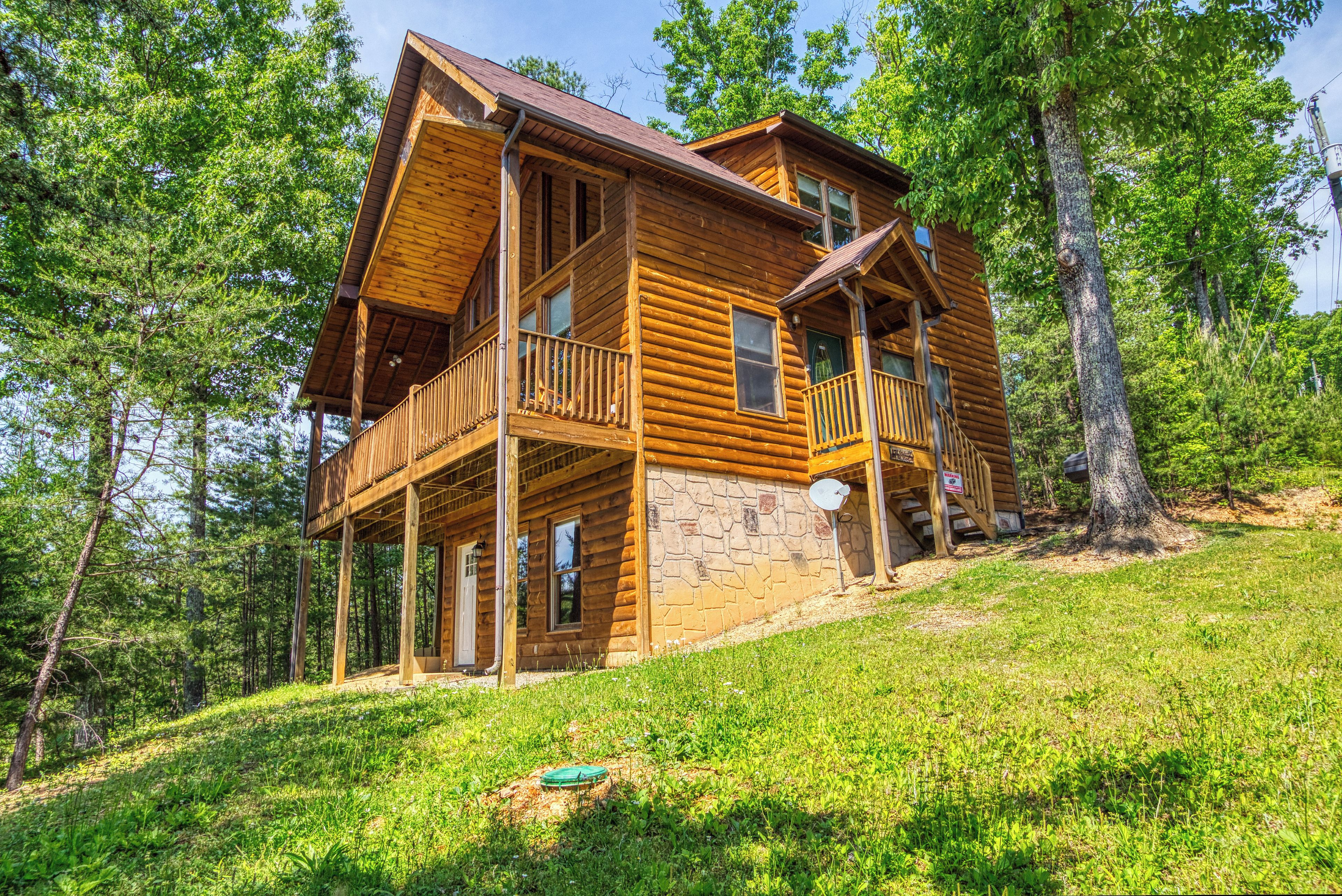 A wooden cabin with a stone foundation, a balcony, and a satellite dish.