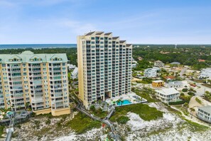A high-rise hotel with multiple floors, a swimming pool, and a beach view.