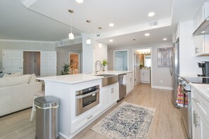 A modern kitchen with white cabinetry, stainless steel appliances, and pendant lighting. - Beachfront end unit w/large private balcony & elevator! (Destin)