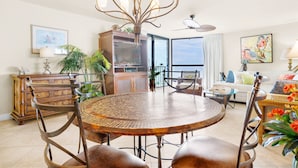 A spacious living room with a round dining table, comfortable seating, a decorative chandelier, and a view to the outside. - ⭐Upgraded-Gulf Views-Walk2Beach-2 Pools+Hot Tub-2BR Mainsail 142⭐ (Miramar Beach)