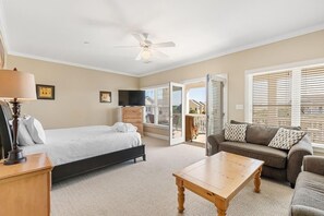 Quarto com cama, mesa de cabeceira de madeira, escrivaninha, sofá e televisão.