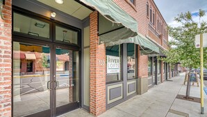 A brick building with a glass door entrance, a sign for 'River Lofts of Salida', and a sidewalk with a tree and a signboard. - Highside Condo @ The River Lofts ~ New condo on the Arkansas River (Salida)