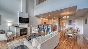 A spacious living room with a fireplace, a dining area with a wooden table, and a kitchen with modern appliances. - Highside Condo @ The River Lofts ~ New condo on the Arkansas River (Salida)