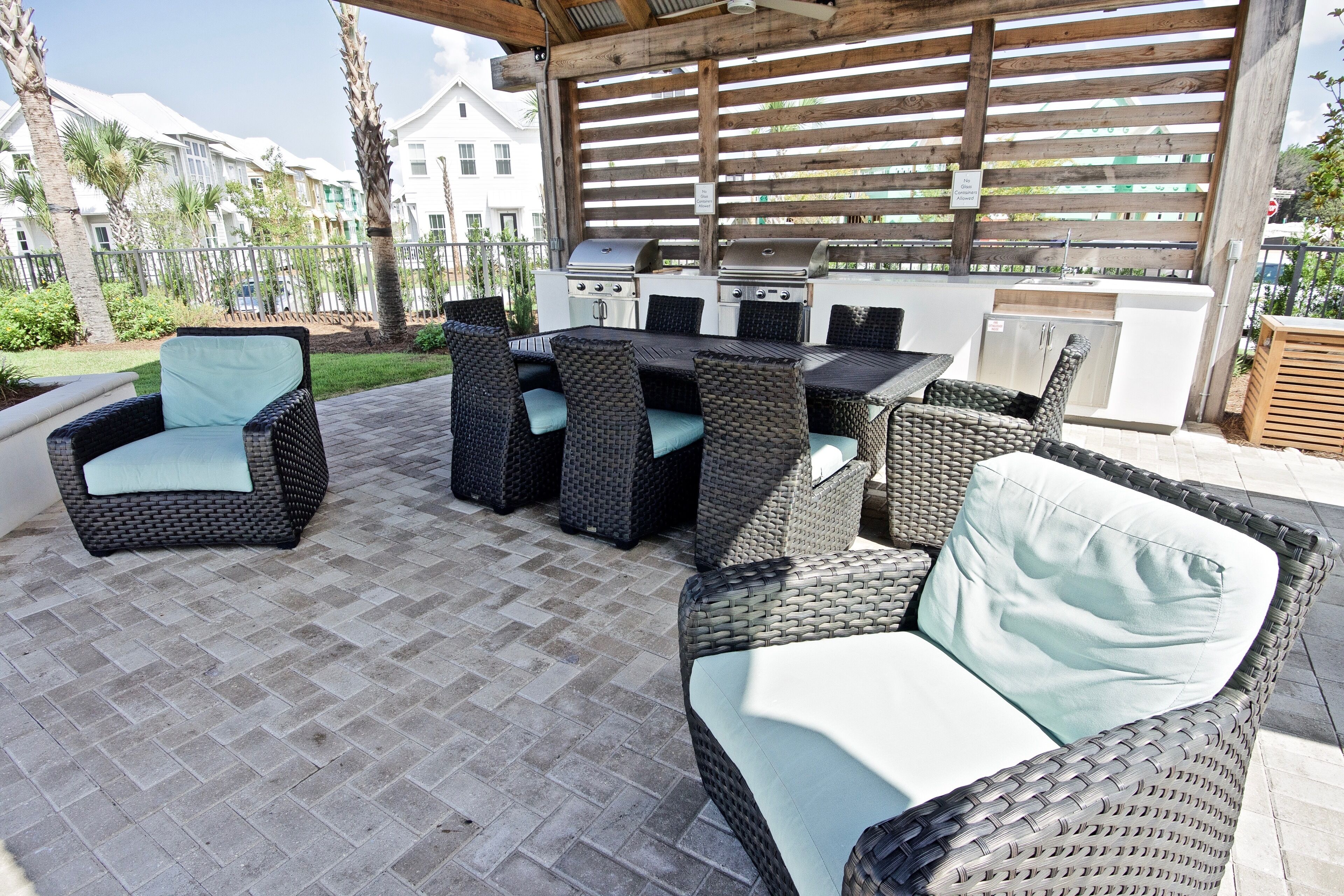 Une terrasse extérieure aménagée avec des meubles en osier, un barbecue et une vue sur des immeubles d’habitation.