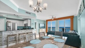 Ein geräumiges Wohnzimmer mit einem großen Esstisch, einer Couch und Blick aufs Meer.