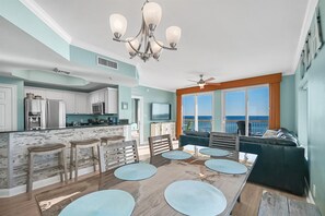 Une cuisine spacieuse avec des meubles blancs, un îlot central et un coin repas comprenant une grande table et des chaises.