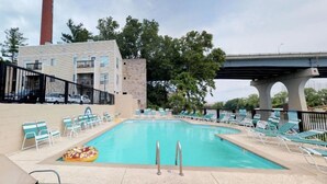 A swimming pool with lounge chairs and a building in the background. - Riverfront Oasis| Pool | King Bed Walk to Broadway (Nashville)