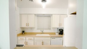 A compact kitchen with white cabinets, a sink, a coffee maker, and a dishwasher. - Riverfront Oasis| Pool | King Bed Walk to Broadway (Nashville)