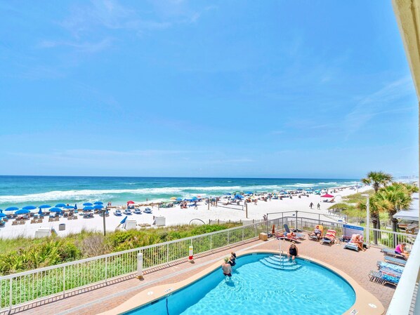 Relax by the pool or on the adjacent beach, surrounded by lounge chairs and umbrellas.