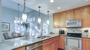 Una cocina moderna con armarios de madera, electrodomésticos de acero inoxidable y encimera de granito.