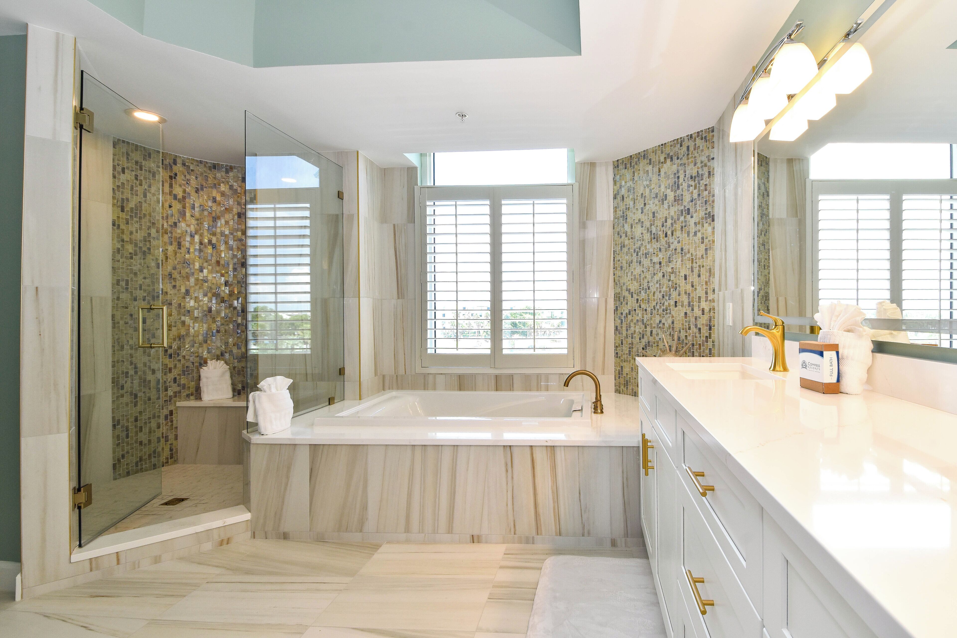 A modern bathroom with a large bathtub, a glass shower enclosure, and a vanity with a sink and mirror.