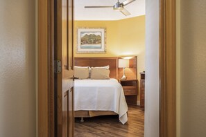 A hotel room with a bed, bedside table, lamp, and a ceiling fan.