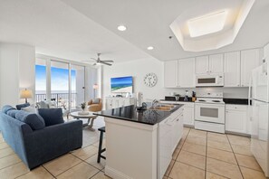 Een moderne keuken met witte kasten, een centraal eiland en een zithoek met een blauwe bank en een tafel.