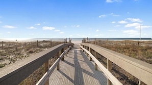 A wooden boardwalk leading to a beach with a clear sky. - Lighthouse 304 by Liquid Life (Gulf Shores)