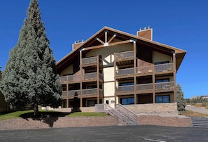 Un edificio de varios pisos con balcones, una escalera y un estacionamiento.