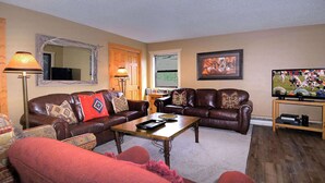 Ein Wohnzimmer mit Ledersofas, einem Couchtisch, einem Fernseher und einem Kamin.